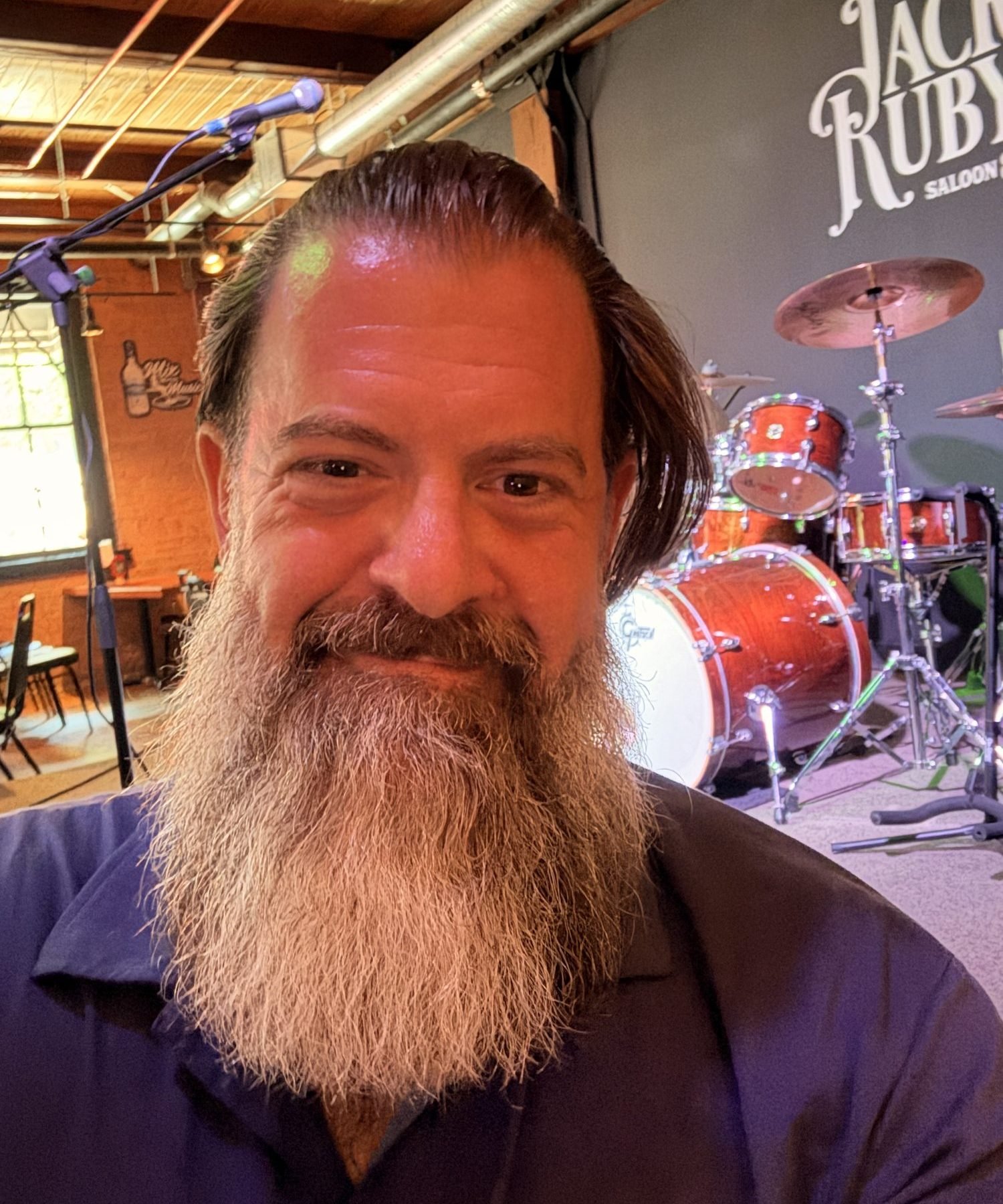 Loren Weisman in front of a drum kit on a small stage, August 1, 2026