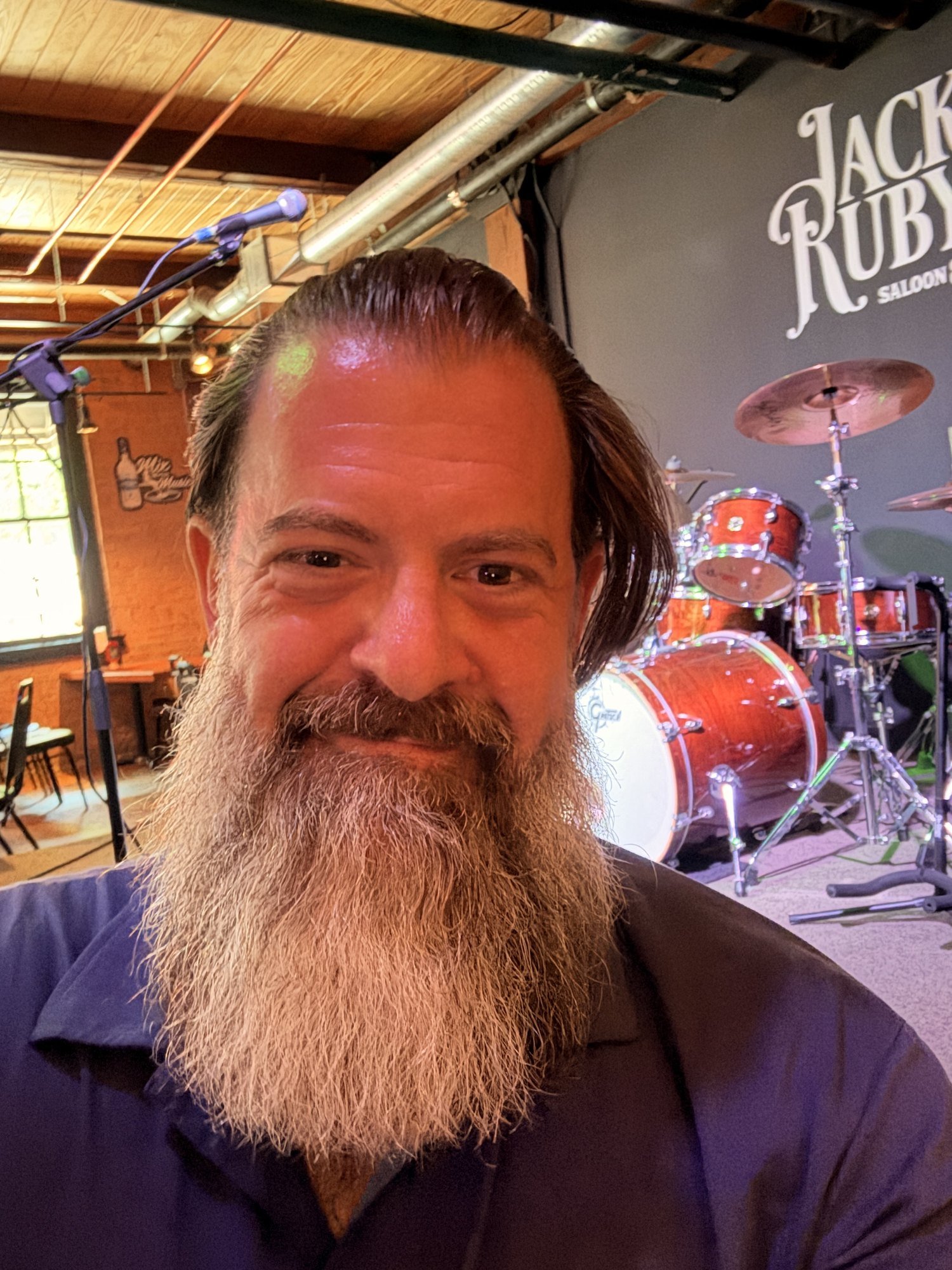 Loren Weisman, author of Music Business For Dummies, standing in front of a drum kit on a stage at a live music venue
