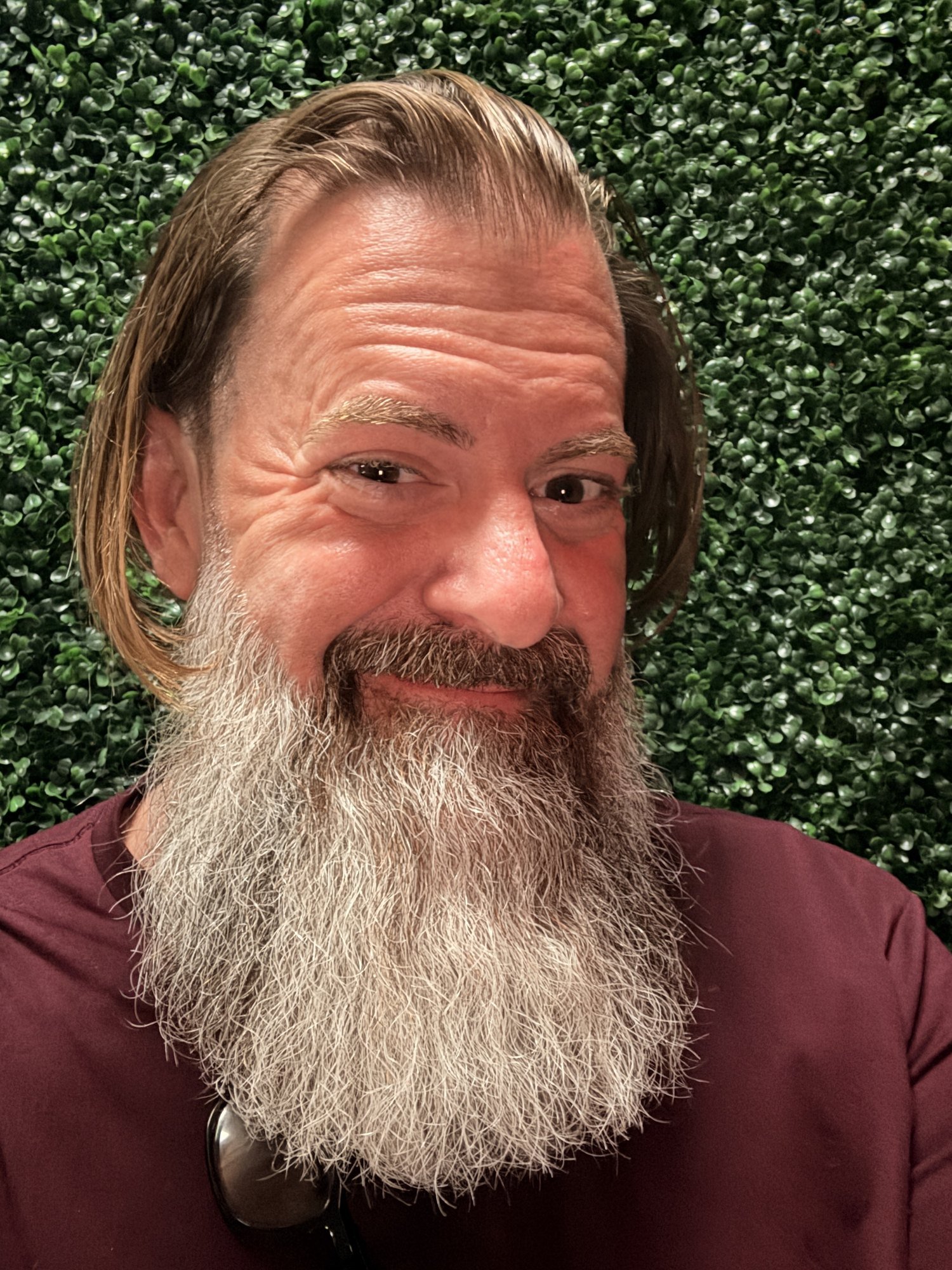 Head and shoulders portrait of speaker Loren Weisman against a green foliage wall