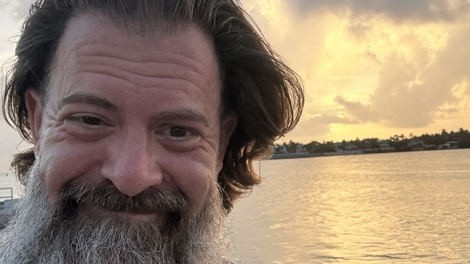 Loren Weisman, host of the Wait What Really OK podcast, at a waterfront at sunset.